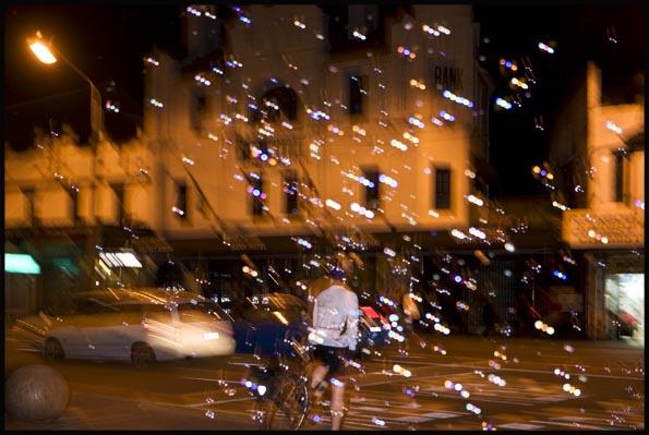 night scene of a busker having blown soap-sud bubbles on Newtown's King street