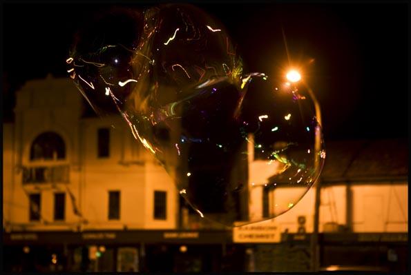night scene of a busker having blown soap-sud bubbles on Newtown's King street