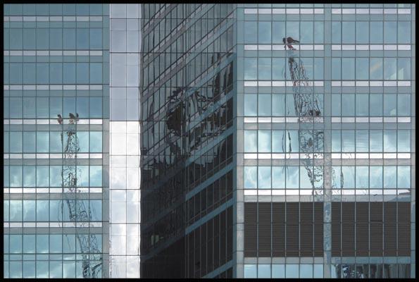 construction cranes reflected in a building's glass-facade