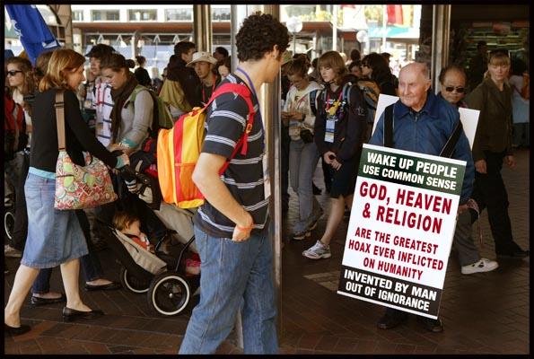 a youth studies a placard 'God, Heaven and Religion the Greatest Hoax' at the Catholic World Youth Day